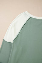 Close-up of the Whispering Willow top showcasing its chic color block design and ribbed detailing.