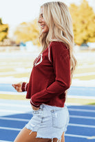 Woman wearing Kickoff Time Top with dynamic football design on a sunny day at a sports field.