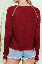 Woman wearing a maroon waffle knit KICKOFF TIME TOP with raglan sleeves, paired with denim shorts, viewed from the back.