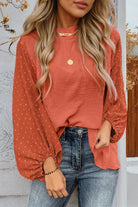 Woman wearing an Autumn Sunset Top with balloon sleeves, rust color, and Swiss dot pattern, paired with jeans.