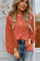 Woman wearing rust-colored Autumn Sunset Top with balloon sleeves and Swiss dot pattern, paired with jeans.