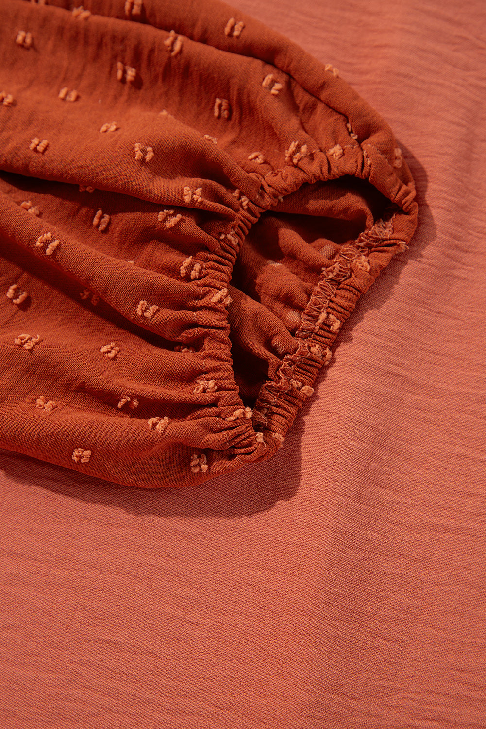 Close-up of rust-colored Autumn Sunset Top with elastic balloon sleeve and Swiss dot pattern on contrasting fabric.