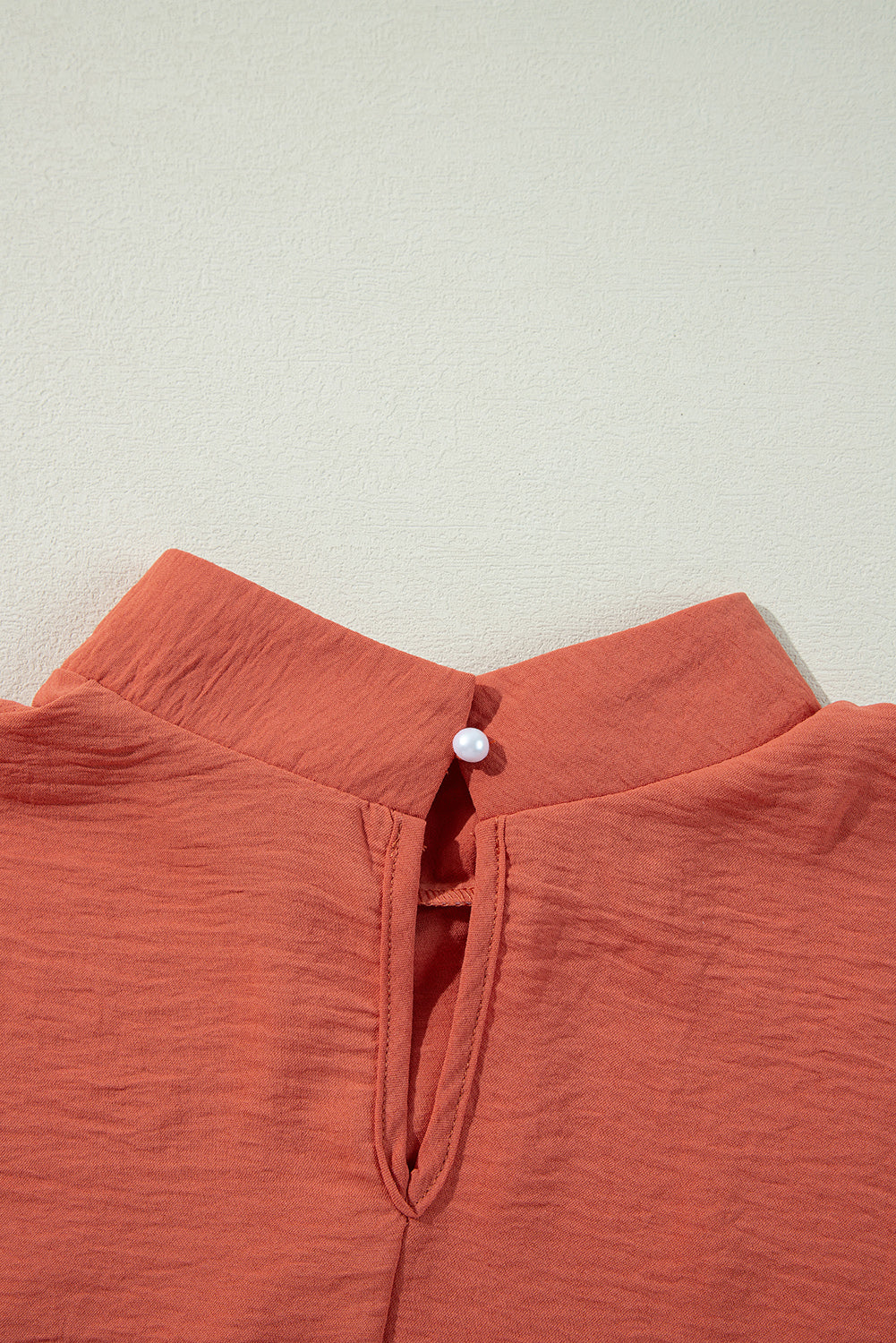 Autumn Sunset Top showing rich rust color fabric with keyhole back detail and gold button closure.