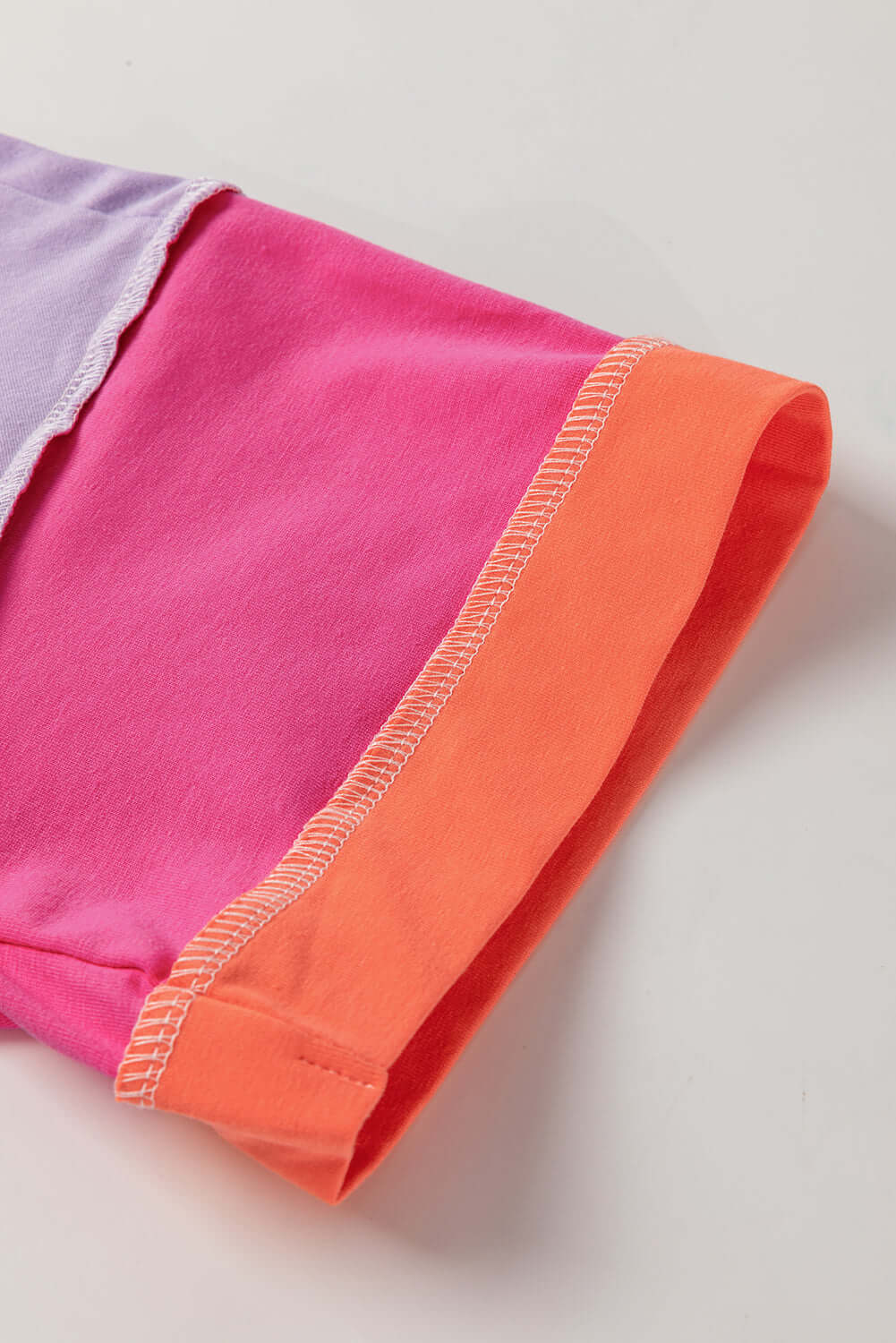 Close-up of the color-blocked sleeve of the Enchanted Aura Top in vibrant pink and orange hues.