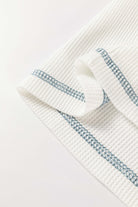 Textured white fabric with blue stitching detail, showcasing a boho-inspired design for casual wear.