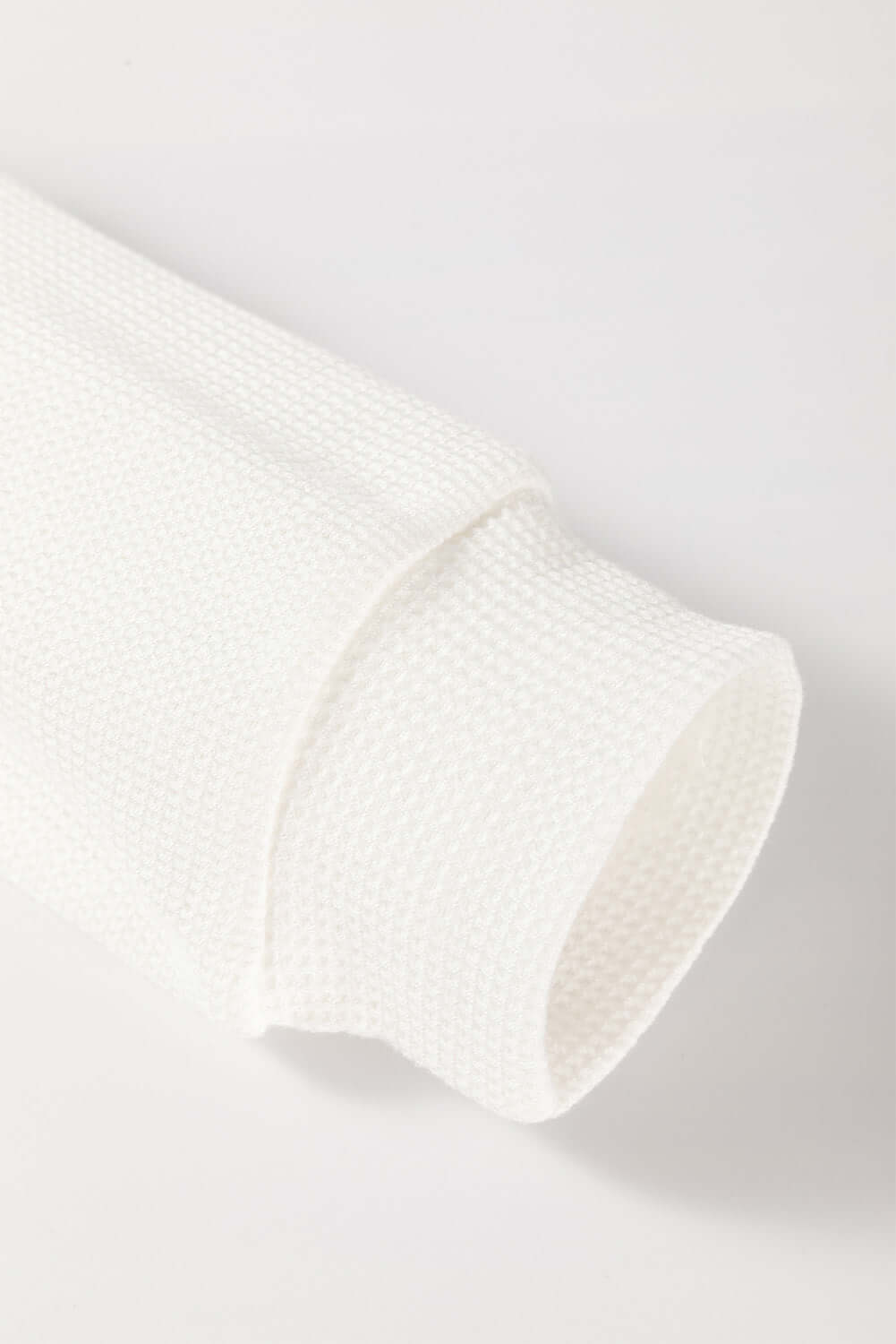 Close-up of the textured sleeve of the Serene Skies Top in white, showcasing its waffle knit design and rolled cuff.