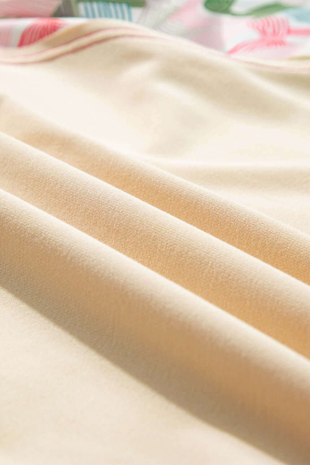 close-up of soft, beige fabric showcasing smooth texture, ideal for versatile clothing items like crewneck tops