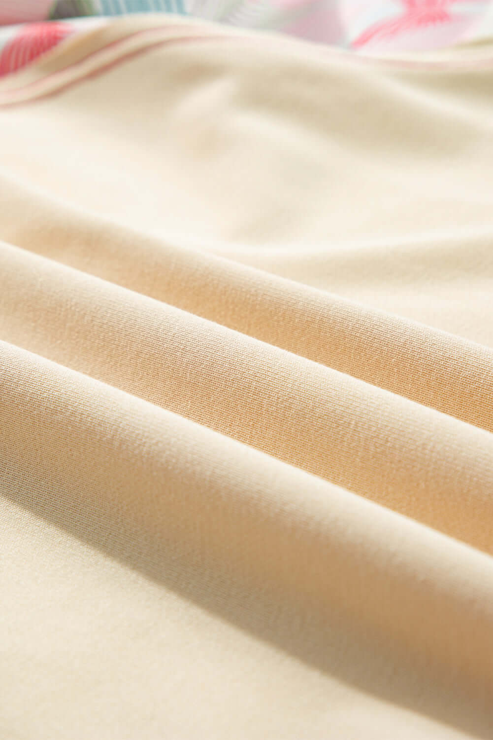 Close-up of soft, cream fabric showcasing smooth folds, ideal for elegant clothing designs.