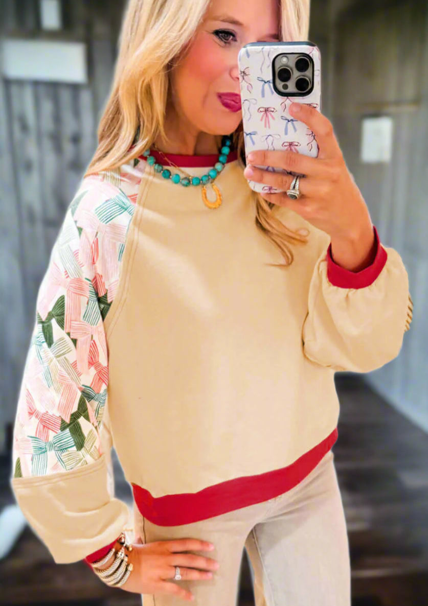 Ties That Bind crewneck top featuring colorful bows on sleeves and vibrant red trim, perfect for versatile styling.