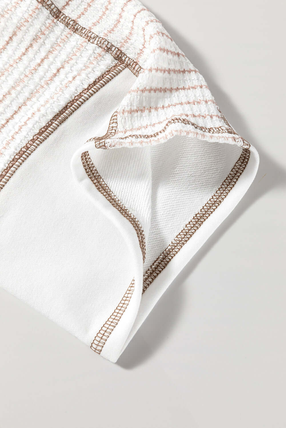 Detail of A Fine Line Top showing striped raglan sleeve and soft fabric in white and tan.