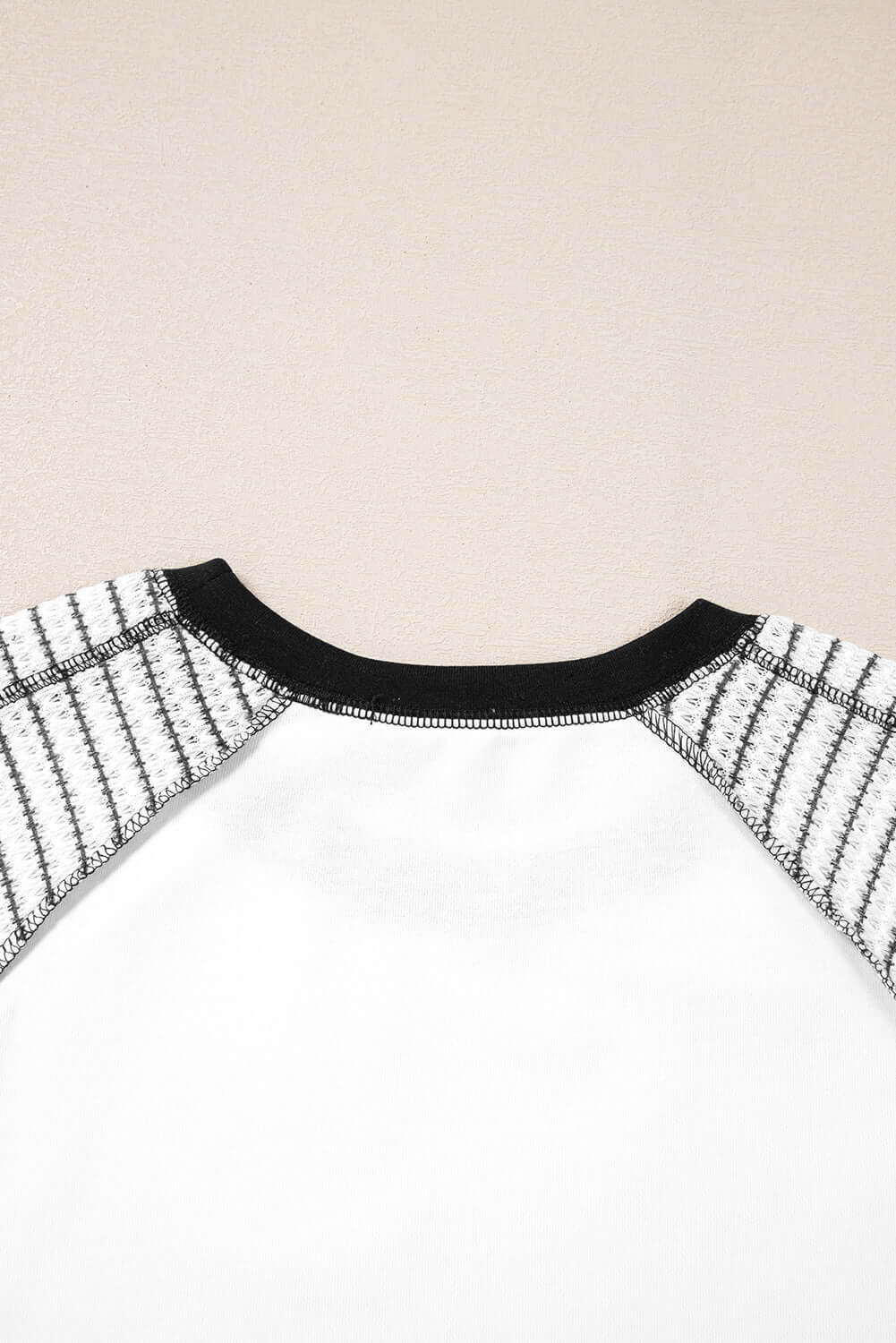 Back view of the Fine Line Top, featuring black striped raglan sleeves and a sleek patchwork design.