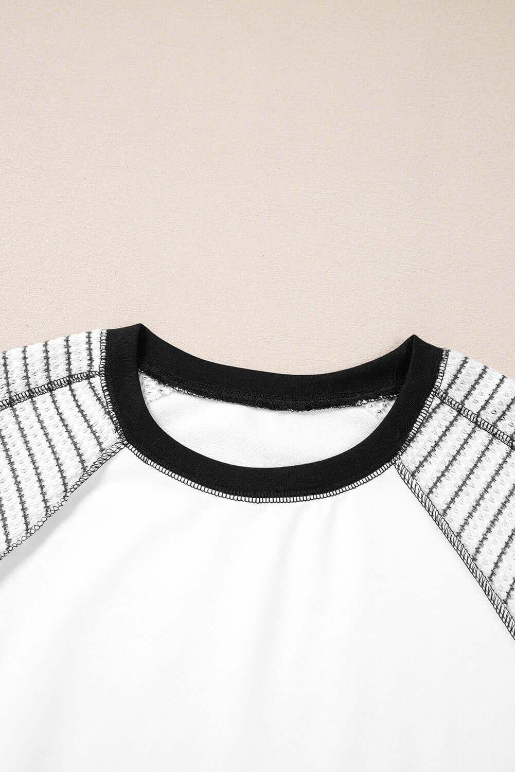 Close-up of the A Fine Line Top featuring patchwork design and striped raglan sleeves in white and black.