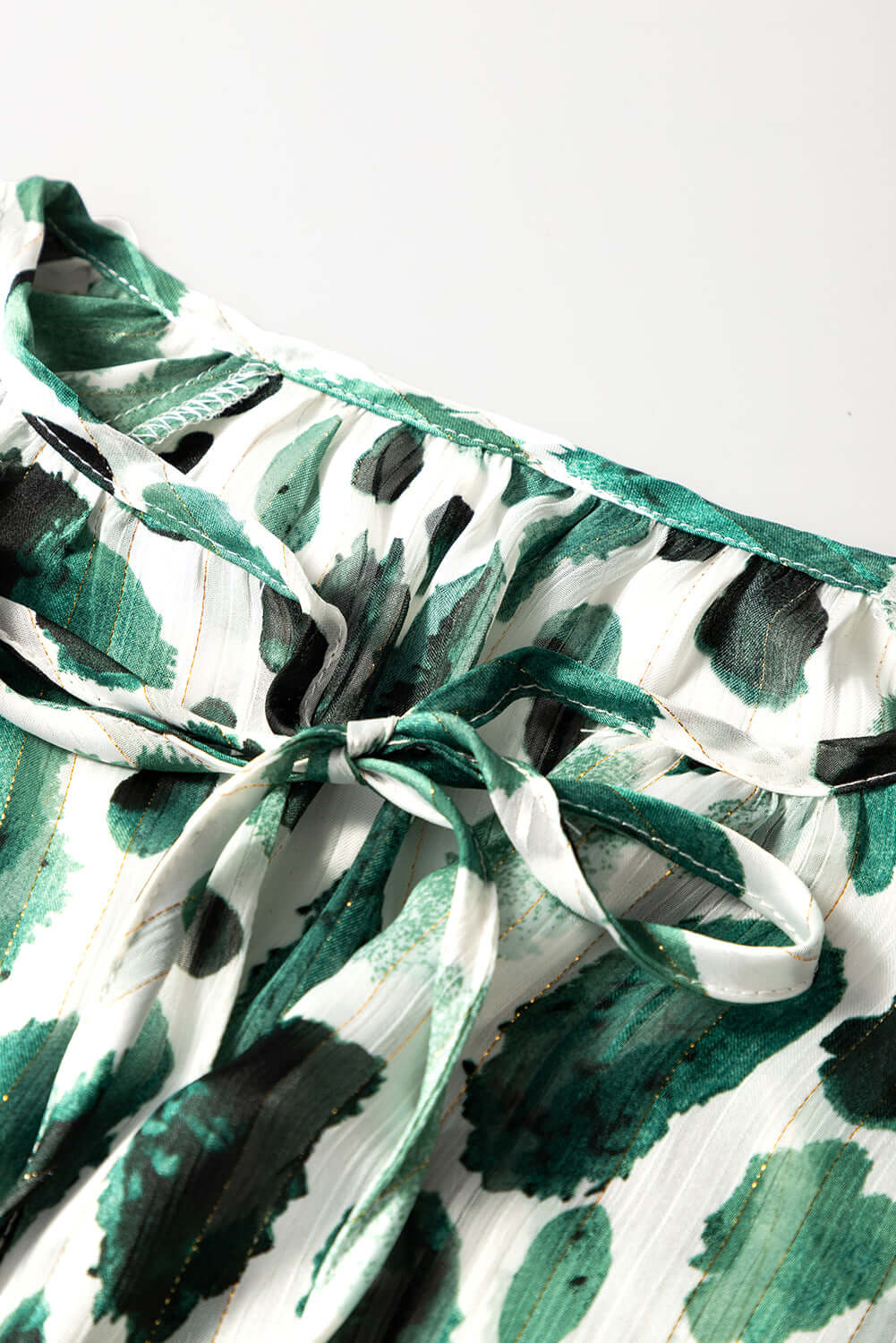 Close-up of the Enchanted Valley Top's spotted design and lace-up detail with ruffled sleeves, in green and white.