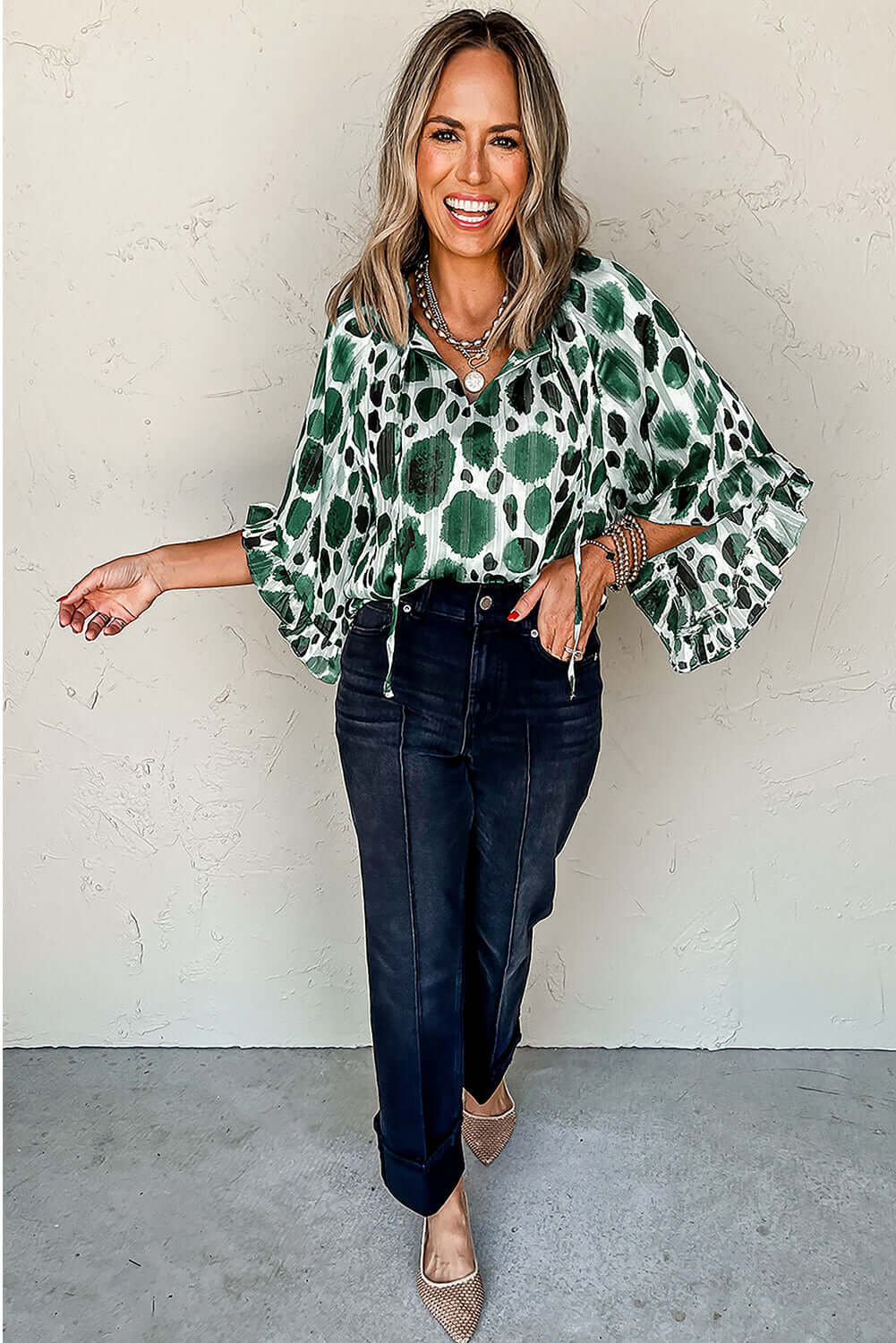 Woman wearing the Enchanted Valley blouse with ruffled sleeves and spotted design, styled with dark jeans.