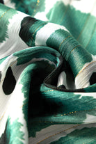 Close-up of Enchanted Valley fabric featuring green spots, pleats, and subtle gold metallic threading.