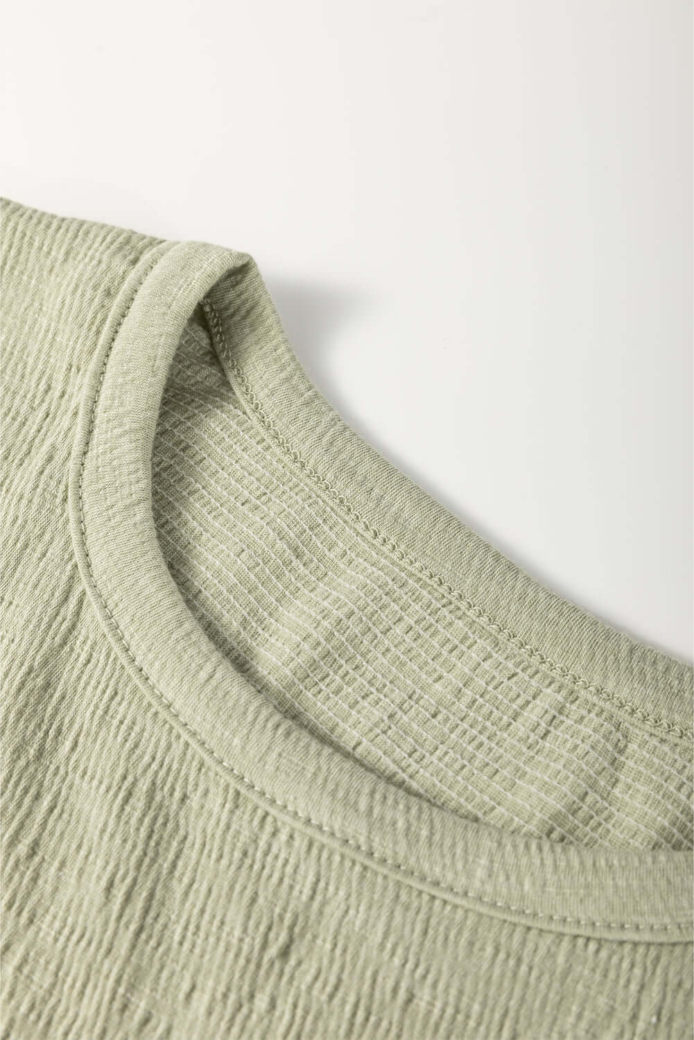 Close-up of the textured crew neck of the Alpine Mist blouse in minty sage, showcasing its soft fabric and stylish design.