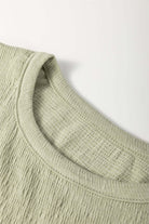 Close-up of the textured crew neck of the Alpine Mist blouse in minty sage, showcasing its soft fabric and stylish design.