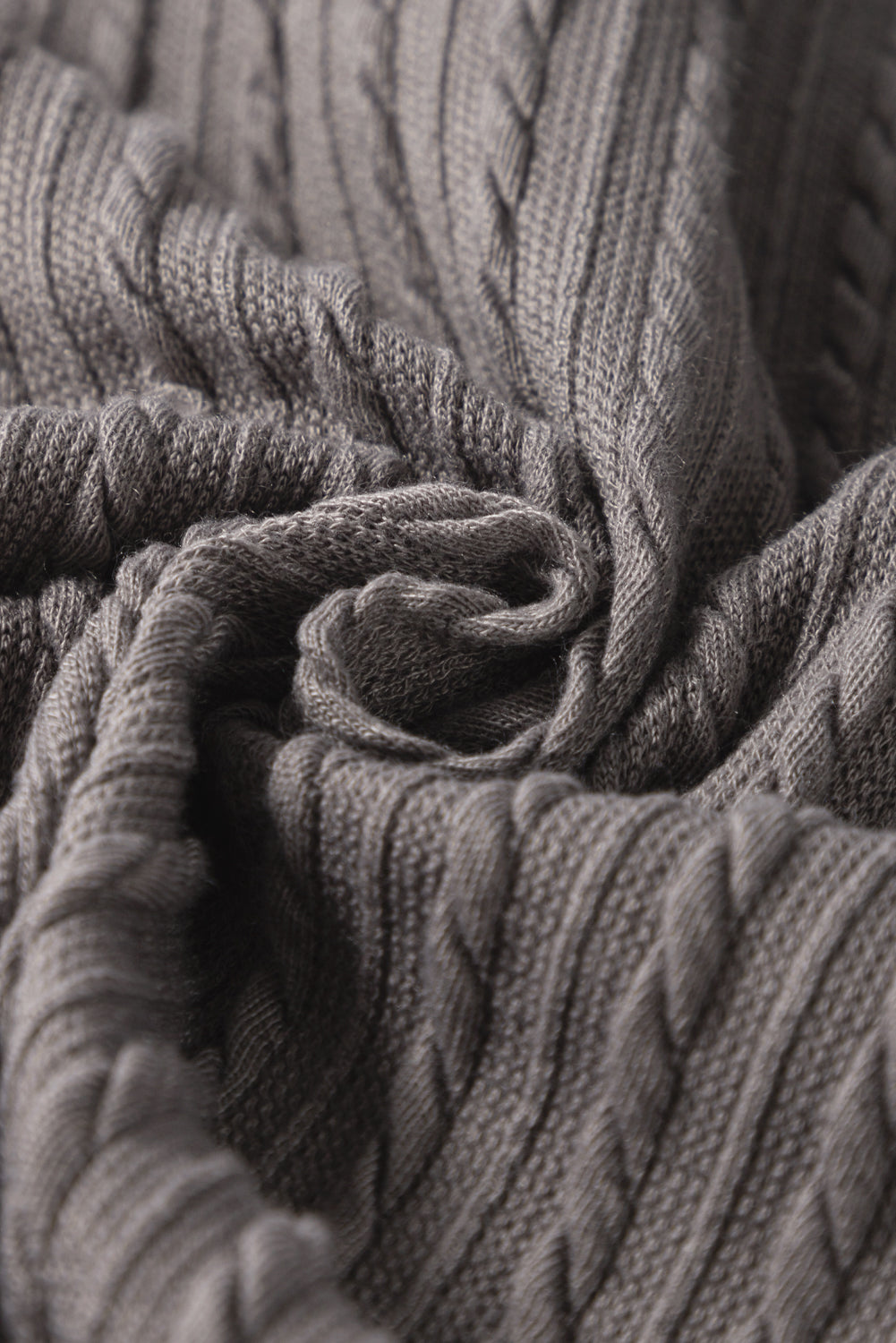 Close-up of soft taupe-gray textured fabric featuring cable-knit design, showcasing its ruffle sleeve top style.