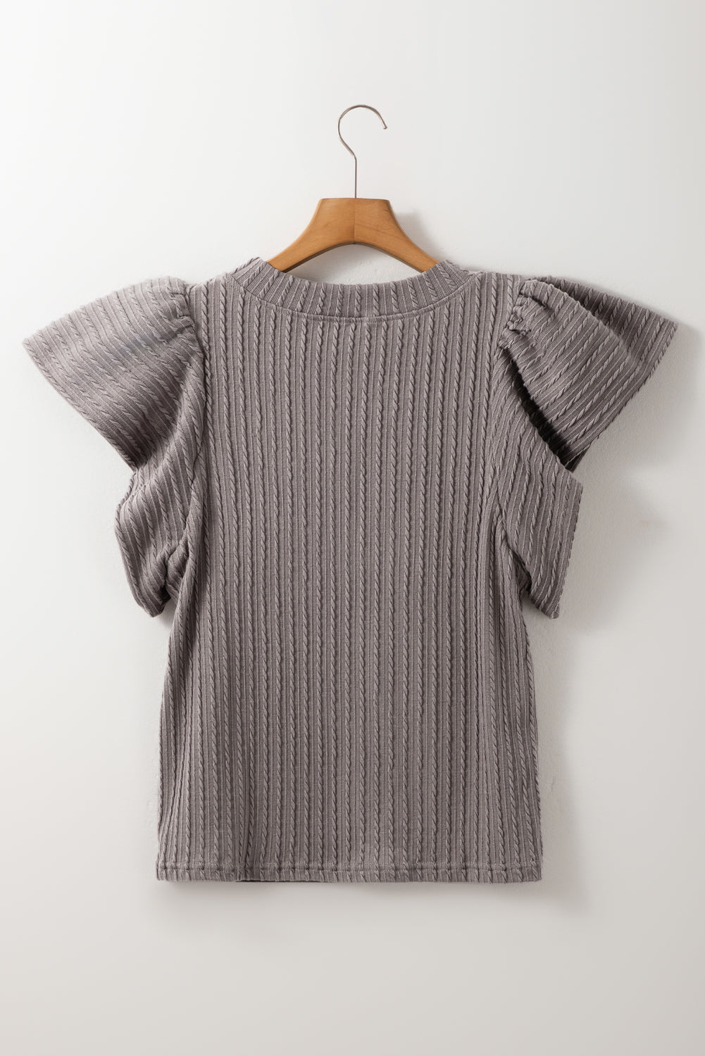 Sound Wave Top in taupe-gray with textured ruffle sleeves, displayed on a hanger against a white background.