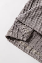 Close-up of the taupe-gray textured fabric of the Sound Wave Top with ruffle sleeves.