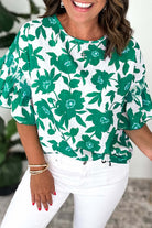 Jade Blooms Top featuring floral print and ruffled sleeves, styled with white pants, perfect for a feminine look.