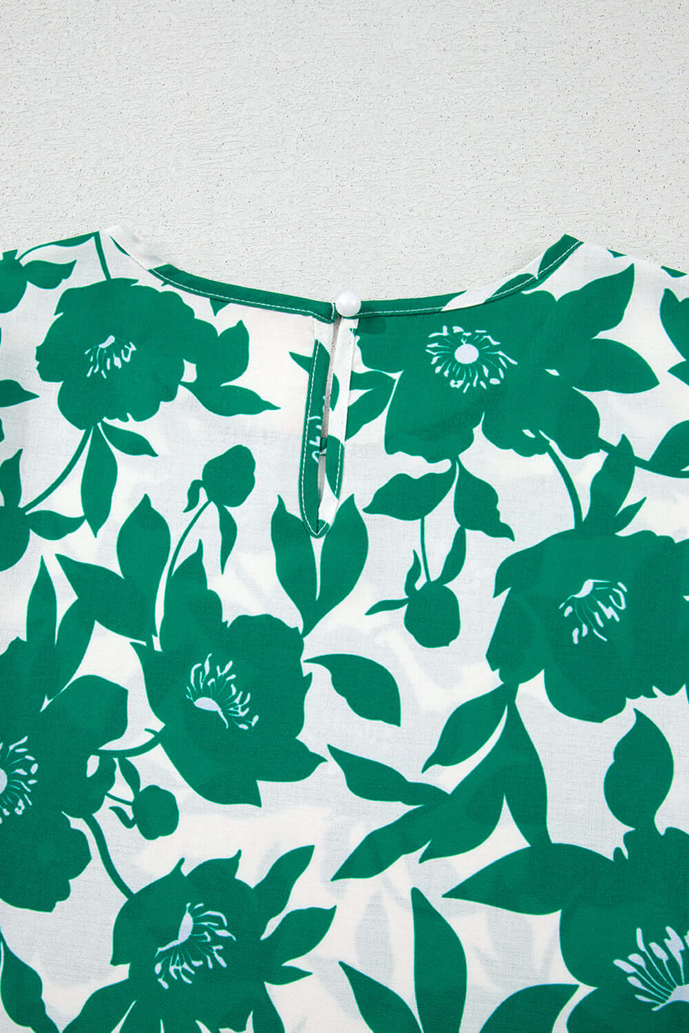 Close-up of the Jade Blooms Top's elegant floral print and button back detailing for a stylish feminine look.