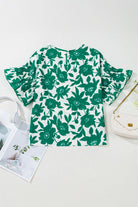 Jade Blooms Top featuring a green floral print and ruffled sleeves, styled with accessories and fashion magazines.