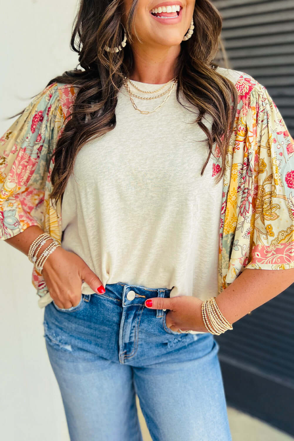 Woman in bohemian Sun Dance top with floral sleeves, styled with jeans and layered necklaces.