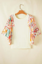 Bohemian style Sun Dance top with floral patchwork print and half batwing sleeves on a hanger.