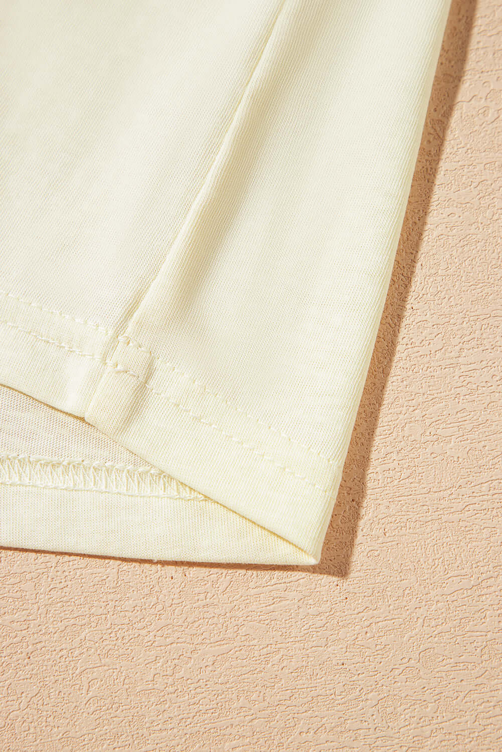 Detail shot of the hem and sleeve of a soft yellow Sun Dance top, highlighting its comfortable fabric and stylish design.