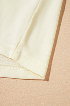 Detail shot of the hem and sleeve of a soft yellow Sun Dance top, highlighting its comfortable fabric and stylish design.