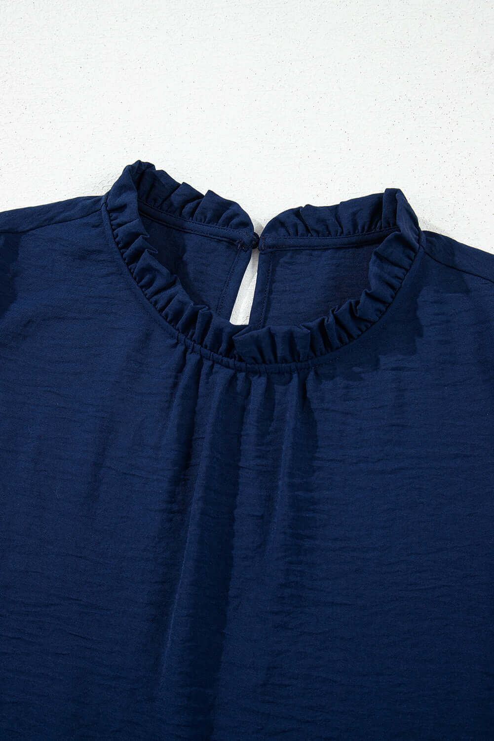 Navy blouse featuring a frilled neckline and chic detailing, perfect for casual or dressy outfits.