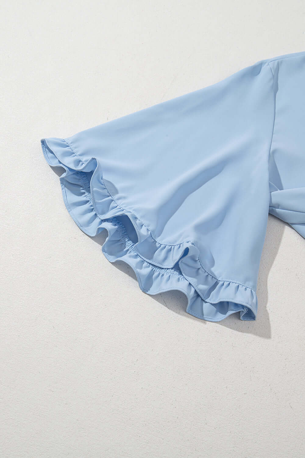 Close-up of light blue Frill Seeker Top with delicate ruffle trim at the sleeves, showcasing breezy charm.