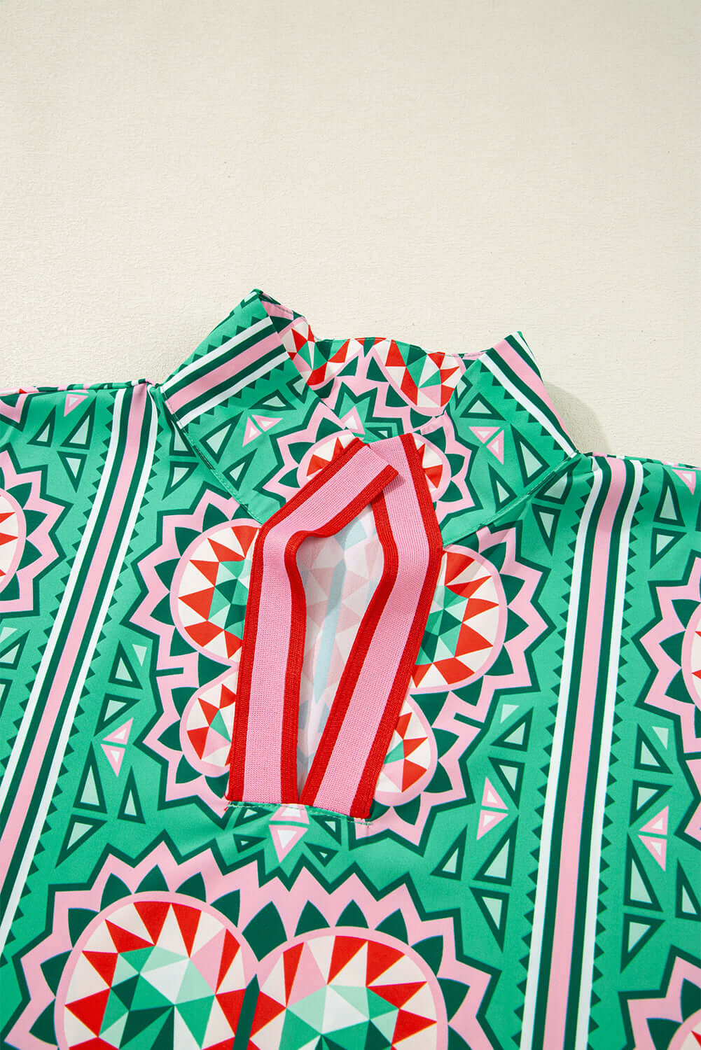Sea green abstract print blouse with a striped collar and V-neckline in bold geometric patterns.