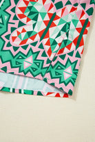 Close-up of Abstract Energy Top featuring geometric patterns in sea green, coral, and blush colors.