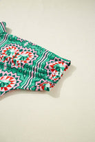 Abstract Energy Top featuring vibrant sea green, coral, and blush patterns with a chic V-neckline.