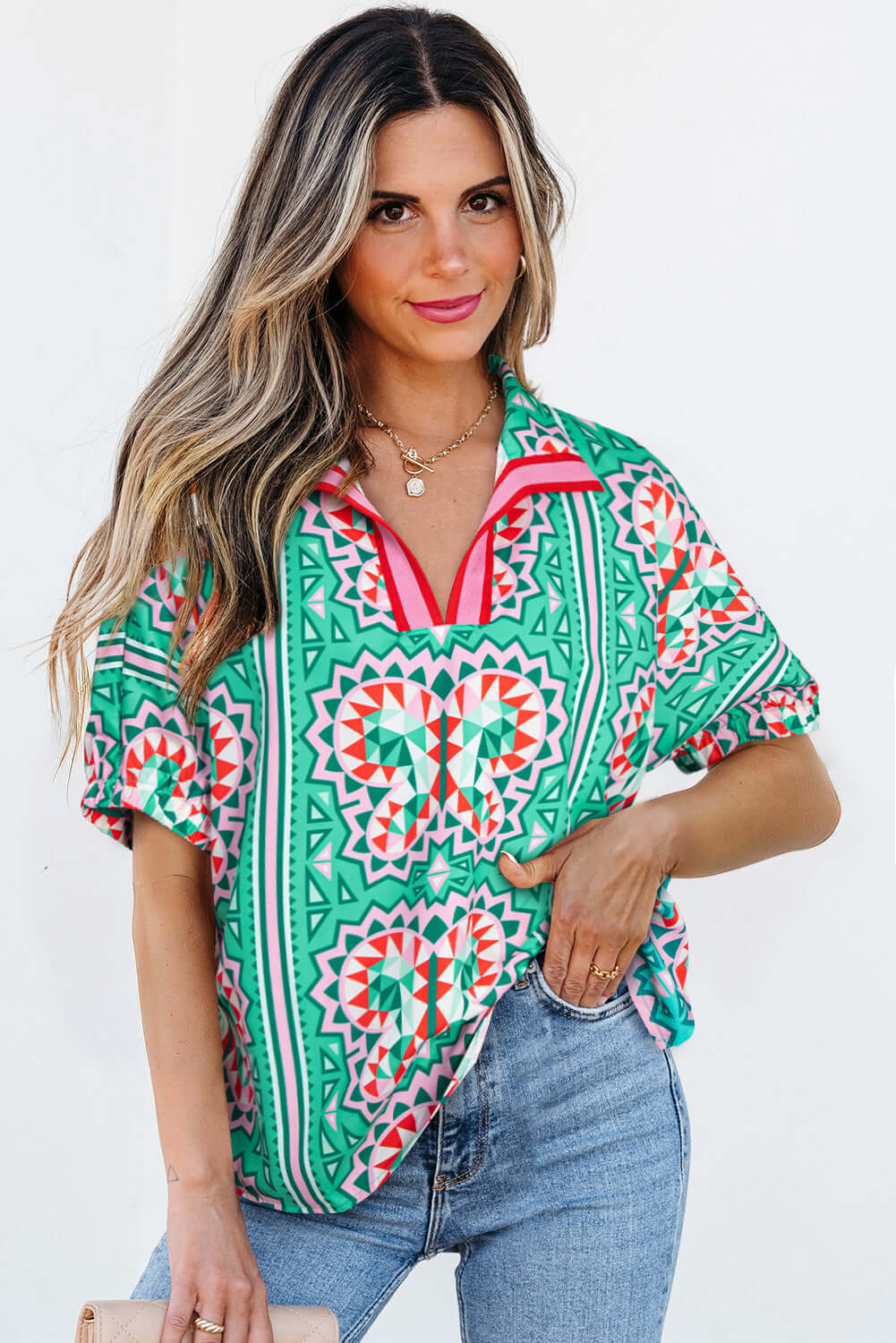 Woman wearing a sea green boho abstract print blouse with geometric patterns and striped collar.