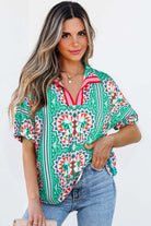 Woman wearing a sea green boho abstract print blouse with geometric patterns and striped collar.