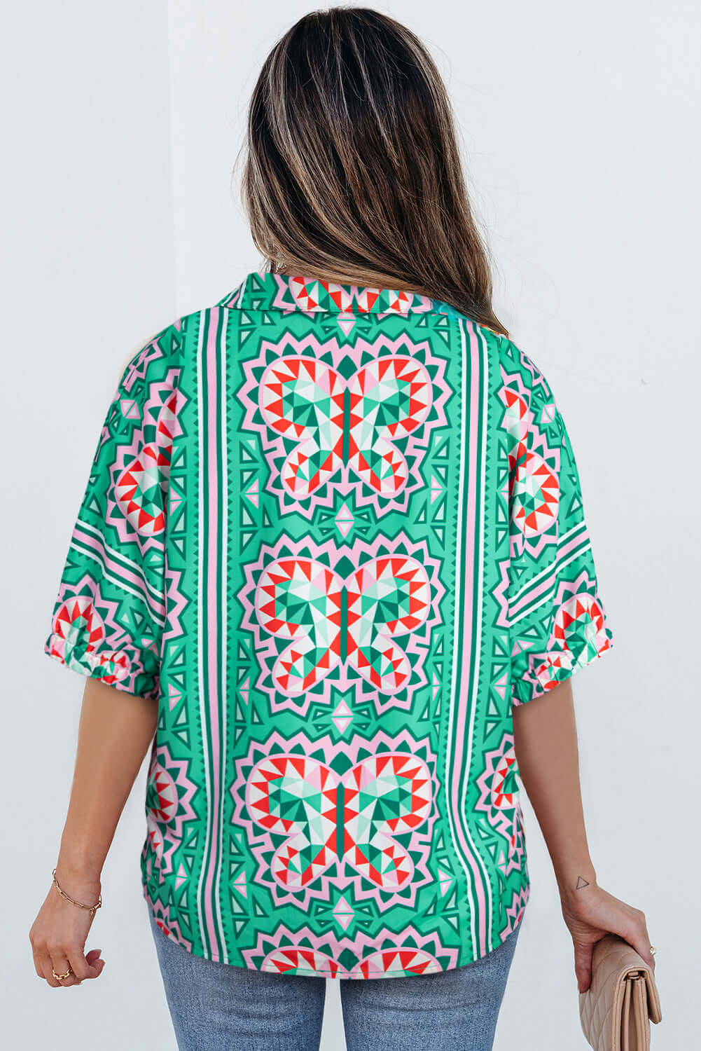 Back view of a sea green abstract print blouse with geometric patterns and short sleeves.