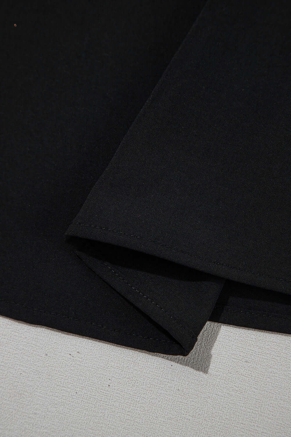 Close-up of black fabric detailing on Fringe Benefits Ruffle Sleeve Blouse, showcasing its soft texture and hem design.