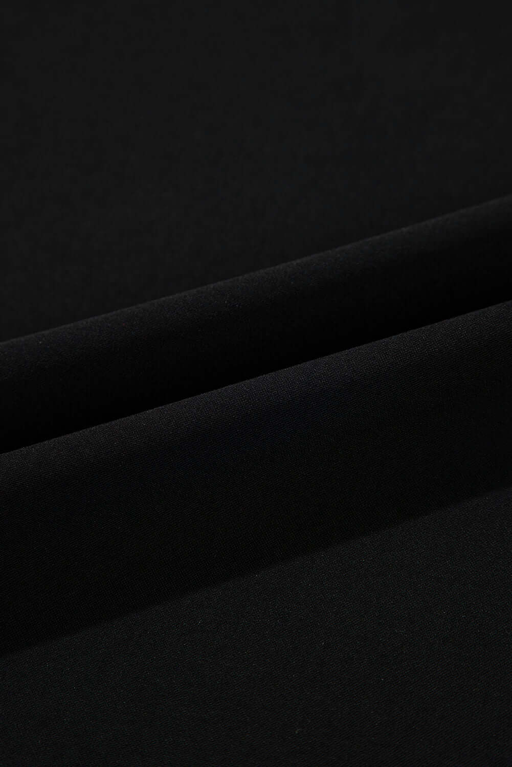 Close-up of luxurious black fabric, showcasing soft texture and smooth folds for stylish apparel.
