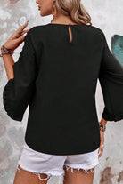 Back view of a black ruffle sleeve blouse paired with white shorts, showcasing elegant design and relaxed fit.