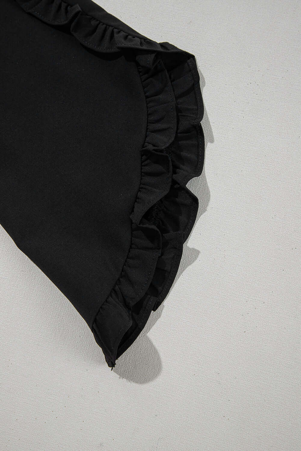 Black ruffle sleeve detail of the Fringe Benefits top, showcasing elegant and flirty design.