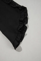 Black ruffle sleeve detail of the Fringe Benefits top, showcasing elegant and flirty design.