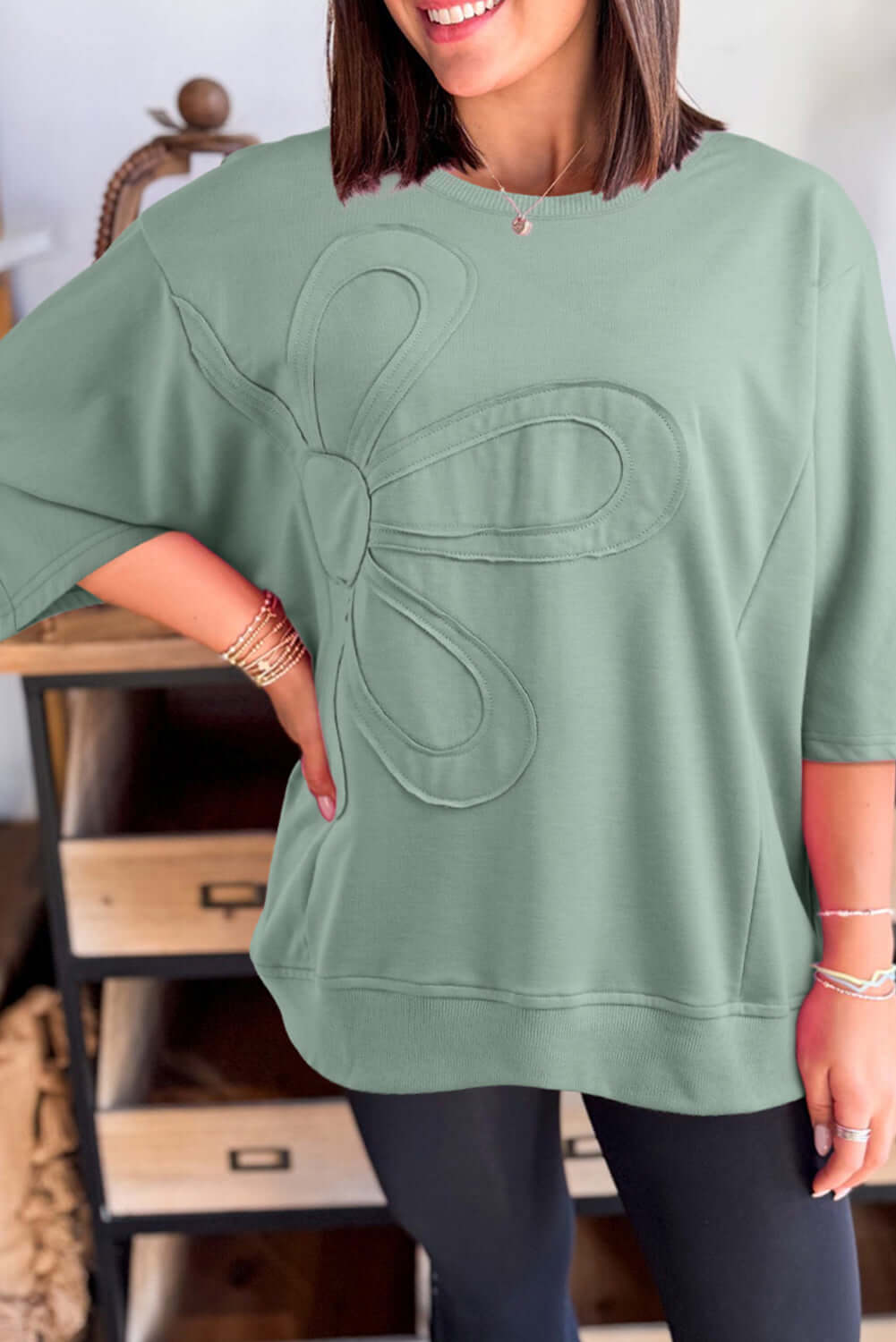 Woman wearing a sea green oversized Flower Theory Top with a floral design and drop shoulder fit.