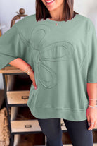 Woman wearing a sea green oversized Flower Theory Top with a floral design and drop shoulder fit.