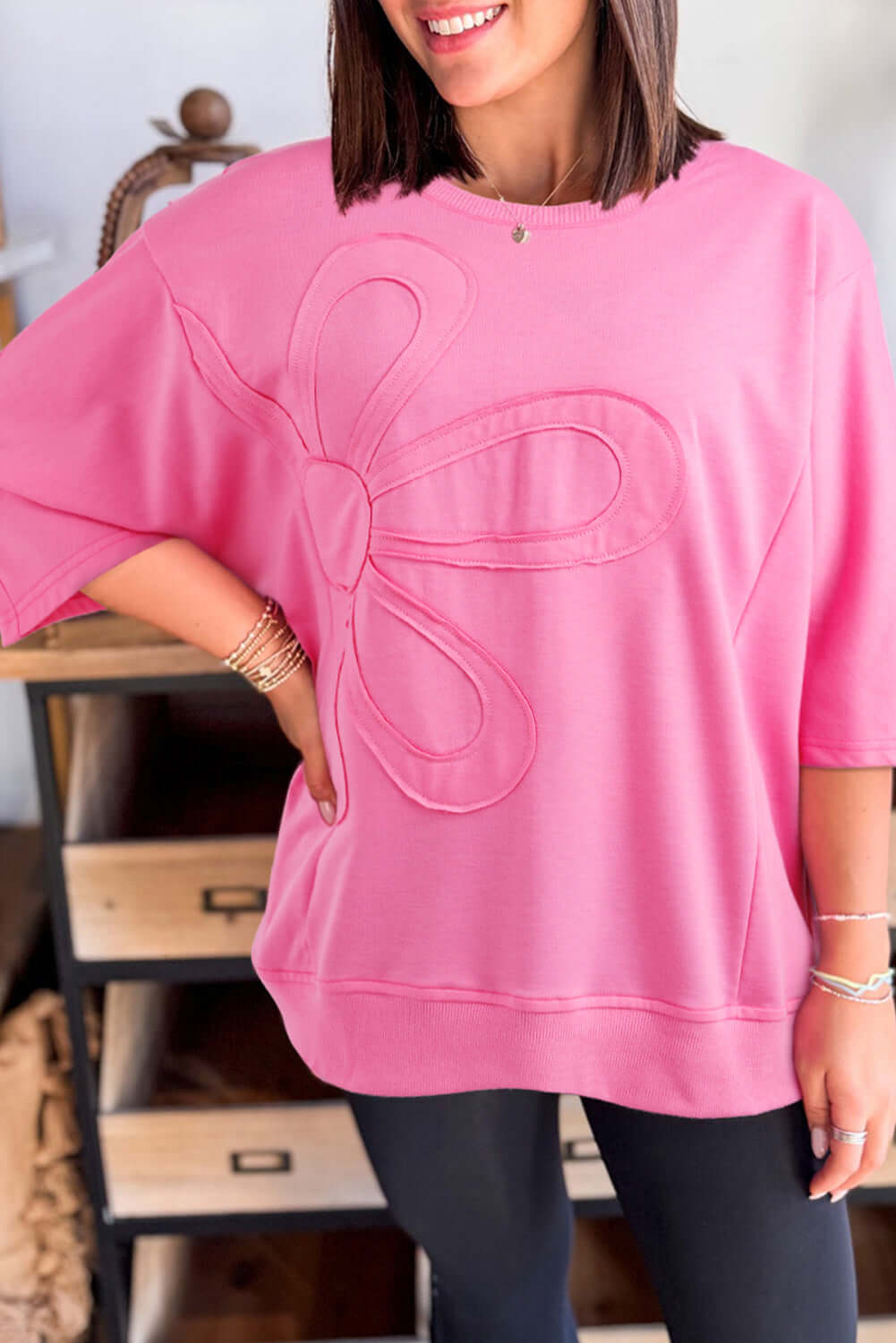 Women wearing taffy pink Flower Theory Top with oversized floral design and drop shoulder fit, showcasing casual style.