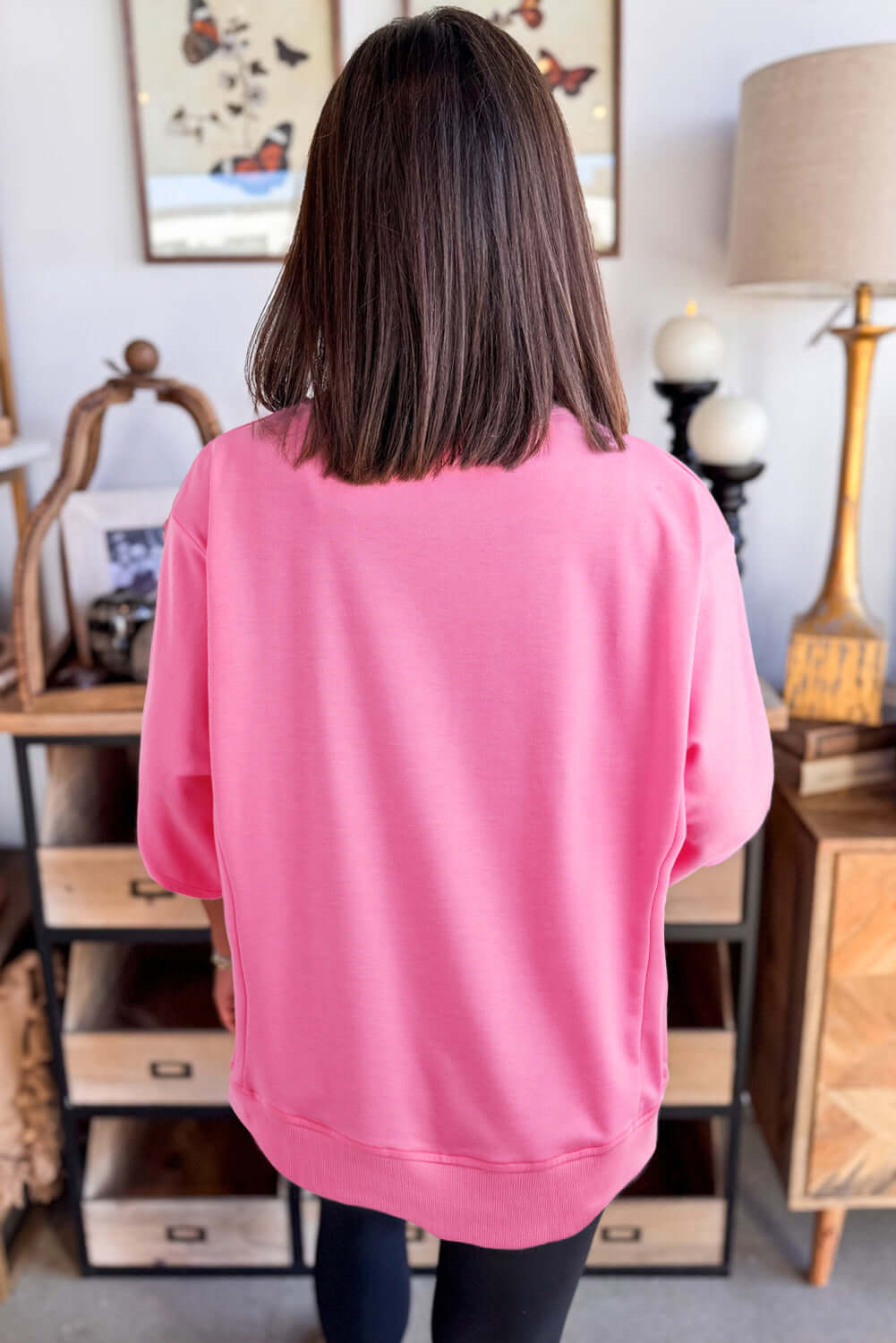 Back view of a model wearing the Flower Theory Top in taffy pink, showcasing its loose fit and casual style.