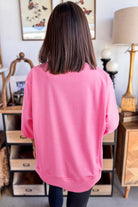 Back view of a model wearing the Flower Theory Top in taffy pink, showcasing its loose fit and casual style.