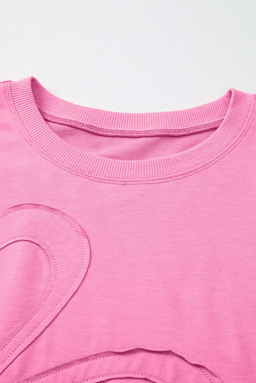 Close-up of Flower Theory Top in taffy pink with oversized floral design and ribbed neckline.